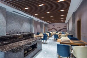Un restaurante con una barra alargada, varias mesas y sillas.