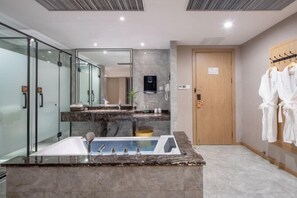 A modern bathroom with a large sink, glass shower enclosure, and a wooden door.