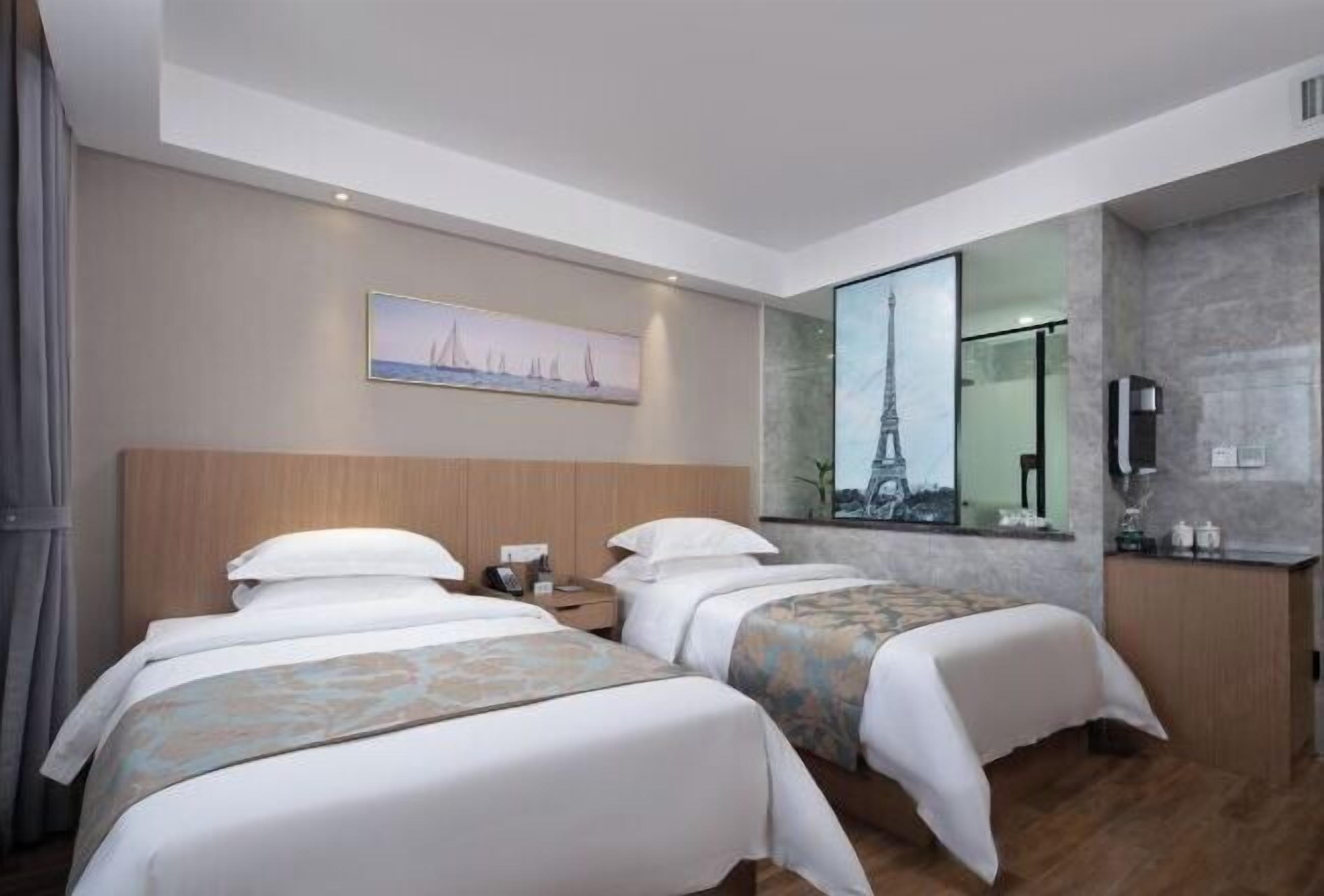 A hotel room with two beds, a large mirror reflecting the Eiffel Tower, a painting of sailboats, and a wooden headboard.