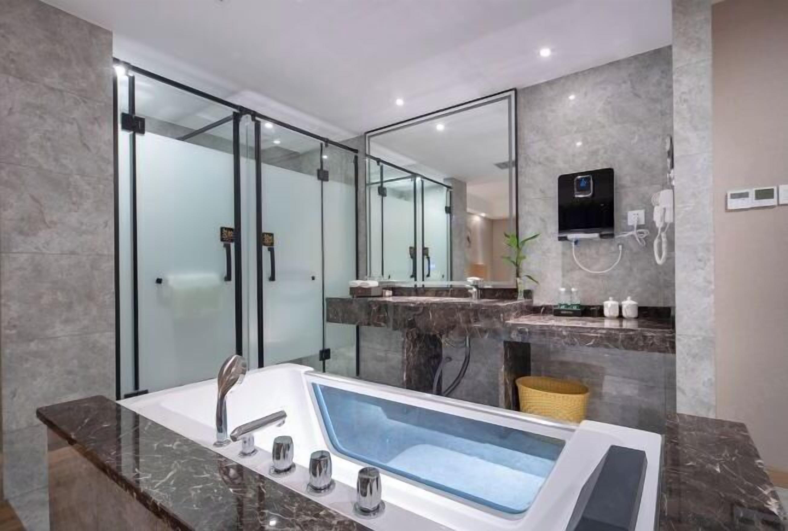 A modern bathroom with a large bathtub, a glass shower enclosure, and a marble countertop.