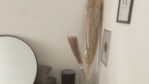 A modern room with a round table, a small side table with a lamp, and a decorative vase with dried plants. - Superb apartment for rent (Paris)