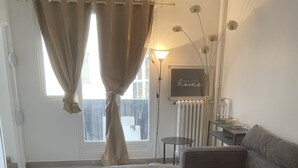 A modern living room with a sectional sofa, a glass coffee table, and a view of the outdoors through a large window. - Superb apartment for rent (Paris)