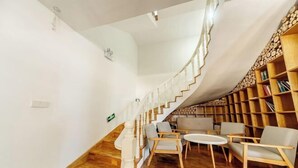 A modern interior with a curved staircase, wooden bookshelves, and a seating area with chairs and a table. - Chaoqibanpo (Zhoushan)