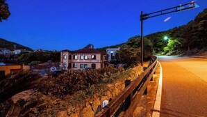 A nighttime view of a coastal road with a building on the left and a streetlight on the right. - Chaoqibanpo (Zhoushan)