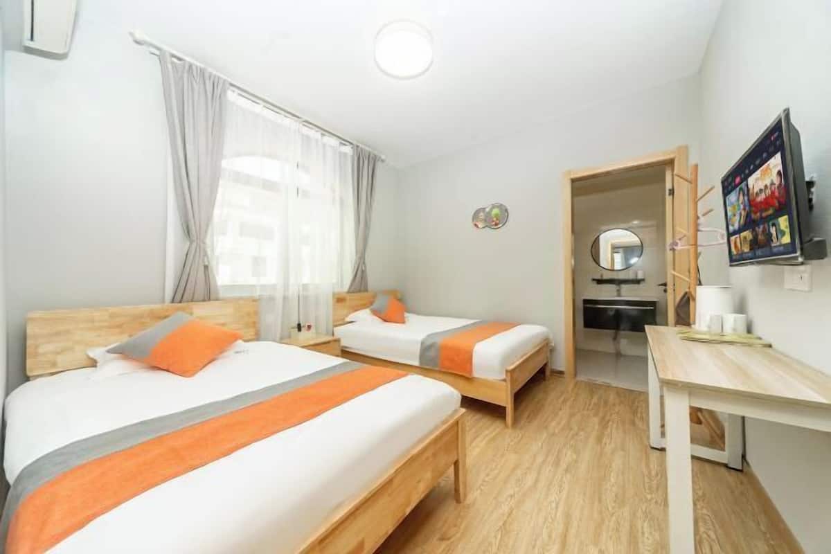 A hotel room with two beds, a desk, a mirror, and a television.