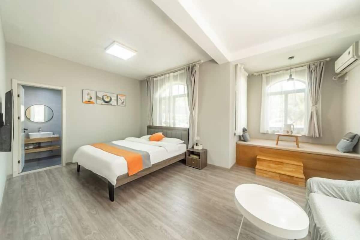 A modern bedroom with a bed, bedside table, and a small seating area with a bench and a chair.