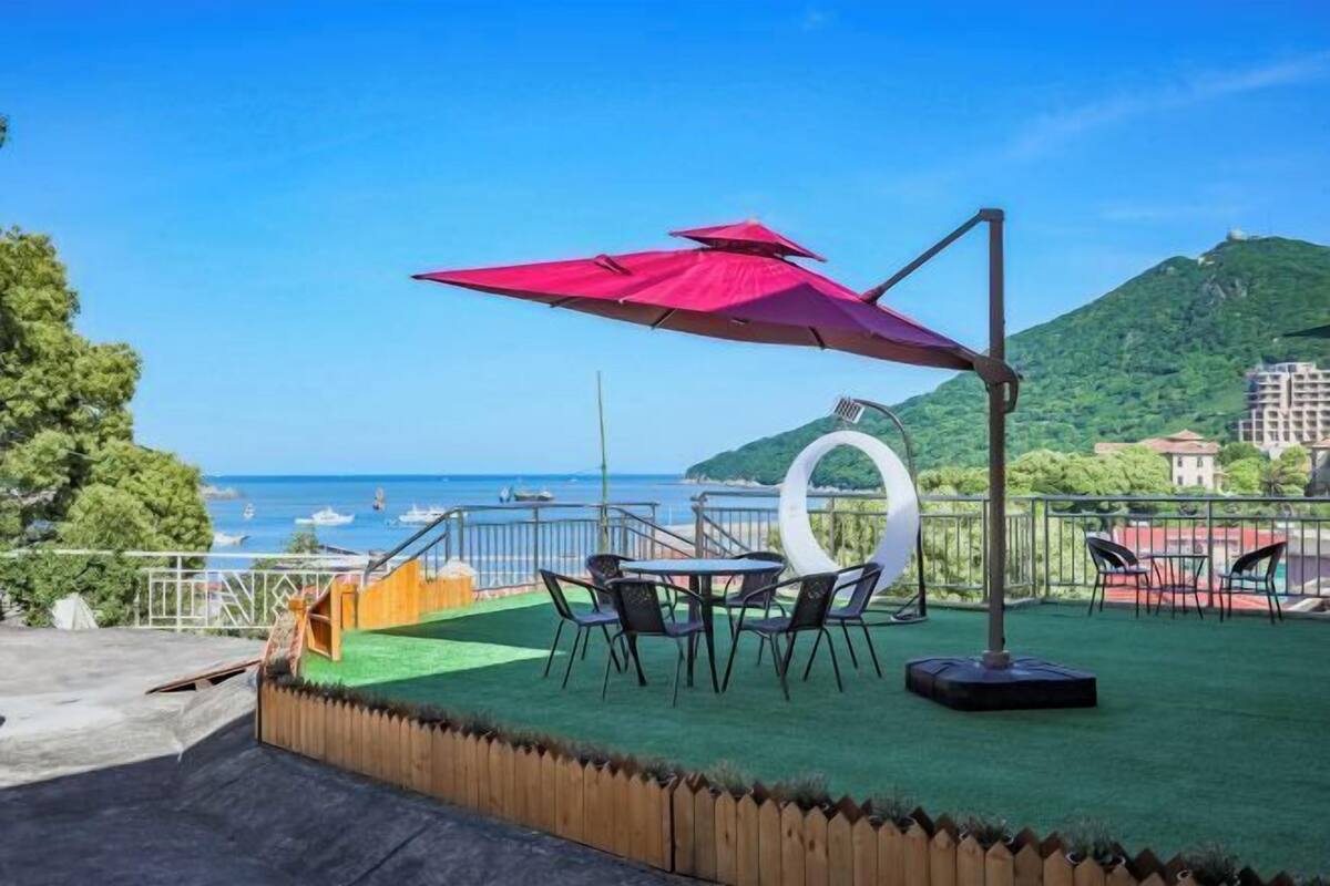 A terrace with a view of the sea, outdoor seating, and a decorative white structure.