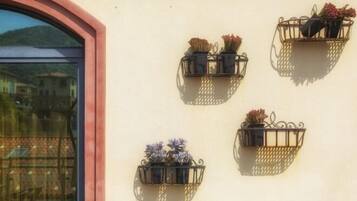 Quatro floreiras fixadas na parede com diversas flores em frente a um muro de edifício.