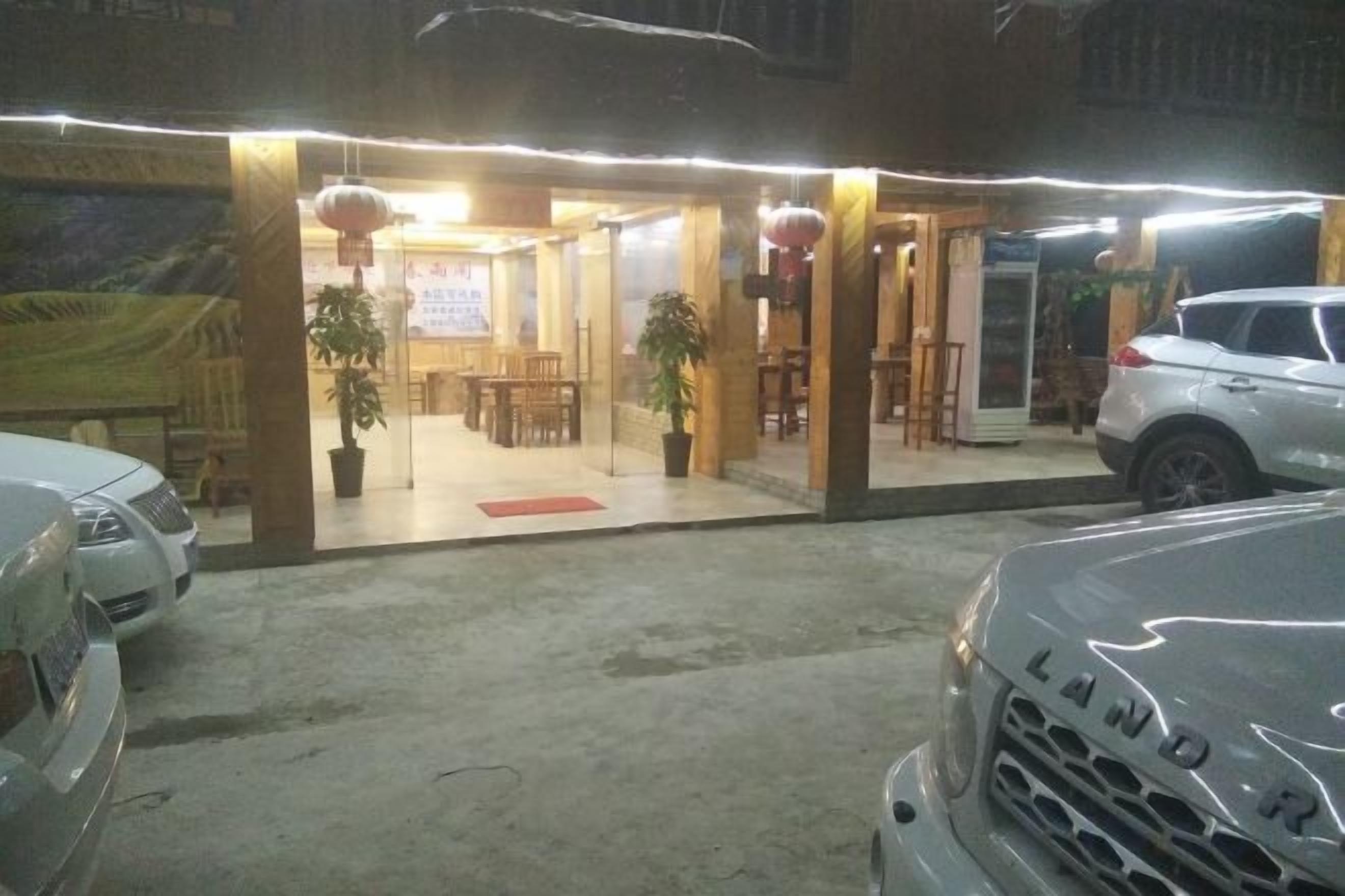Un edificio con entrada cubierta, plantas en macetas y un coche estacionado afuera.