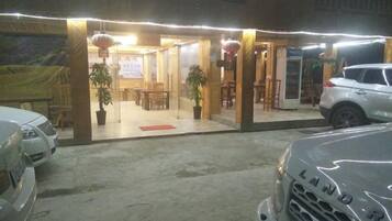 Un edificio con entrada cubierta, plantas en macetas y un coche estacionado afuera.