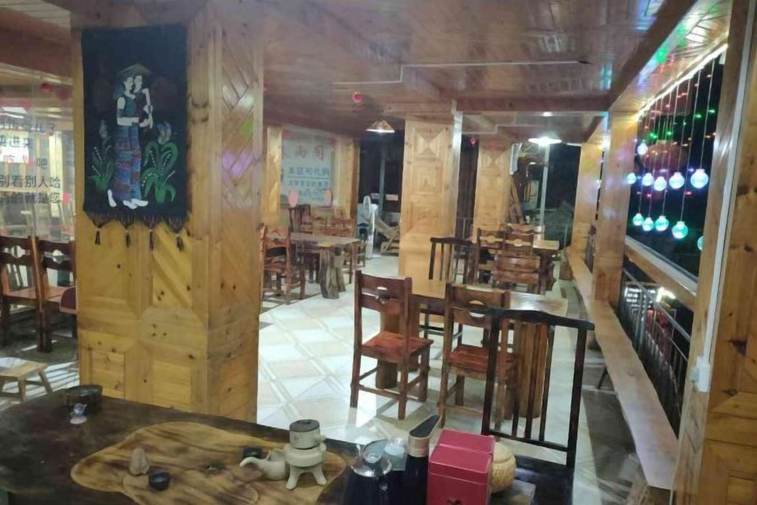 Un interior de restaurante con mobiliario de madera, una zona de bar y una pared con luces colgantes.