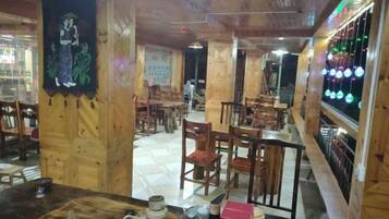 Un interior de restaurante con mobiliario de madera, una zona de bar y una pared con luces colgantes.