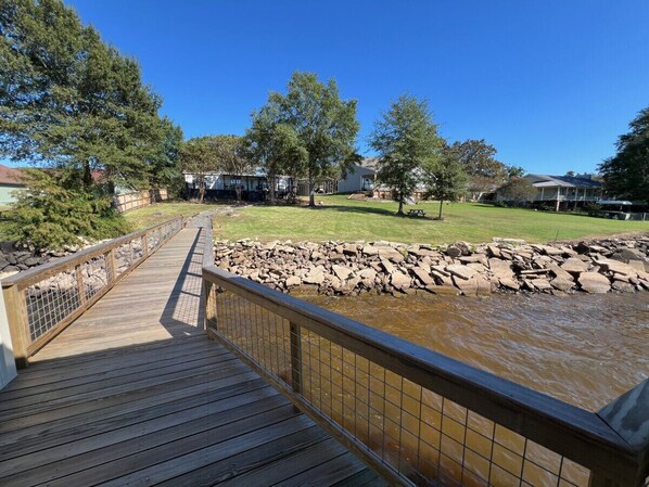 A wooden bridge over a rocky stream with houses in the background.