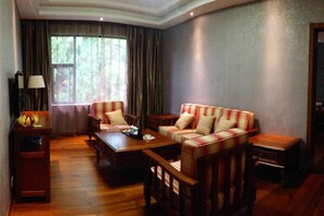 A living room with a sofa set, a coffee table, a TV stand, and a window with curtains. - Lianhu Hotel (Qinglong)