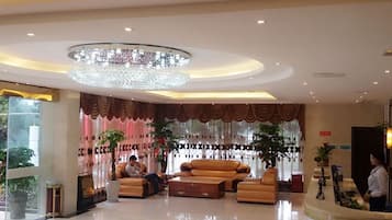 A hotel lobby with a chandelier, seating area, and reception desk.
