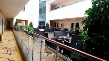 A hotel lobby with a glass elevator, indoor seating area, and a decorative floor.