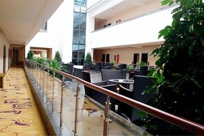 A hotel lobby with a glass elevator, indoor seating area, and a decorative floor.