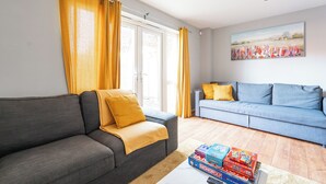 Un salon avec un canapé gris, un canapé bleu et une table basse sur laquelle sont posés des jeux de société.