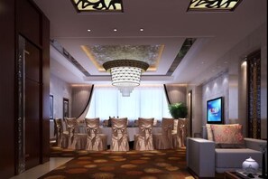 A hotel lobby with a chandelier, seating area, and a television screen.