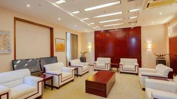 A hotel lobby with multiple seating areas, a flat-screen TV, and a large red accent wall.