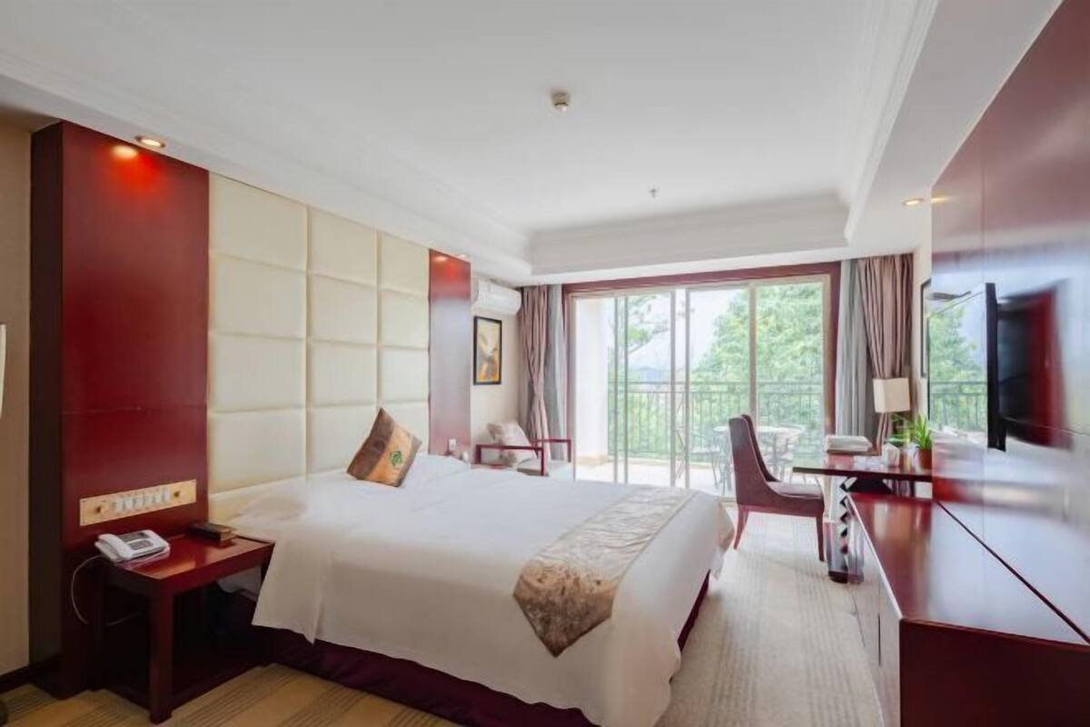 Une chambre d’hôtel avec un grand lit, un bureau, une chaise et un téléviseur.