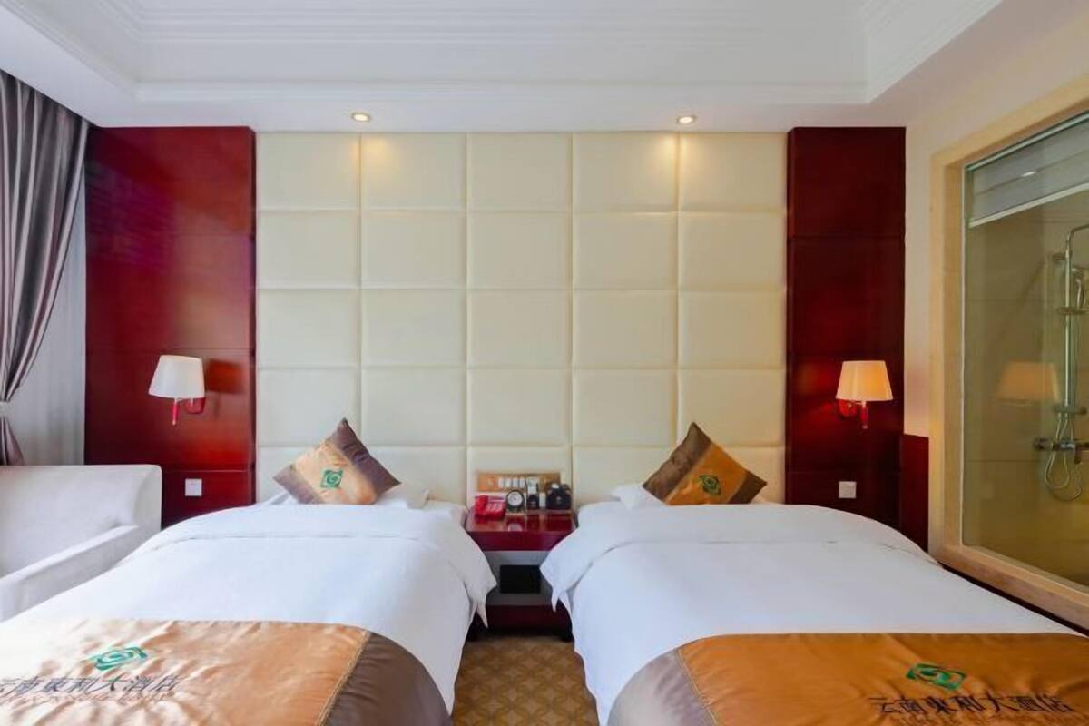 Une chambre d’hôtel avec deux lits, une table de chevet et une douche en verre.
