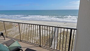 A balcony with a view of the beach and ocean.