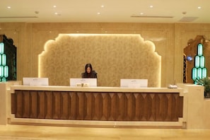 En receptionsdisk med en receptionist, två bärbara datorer och en dekorativ vägg.
