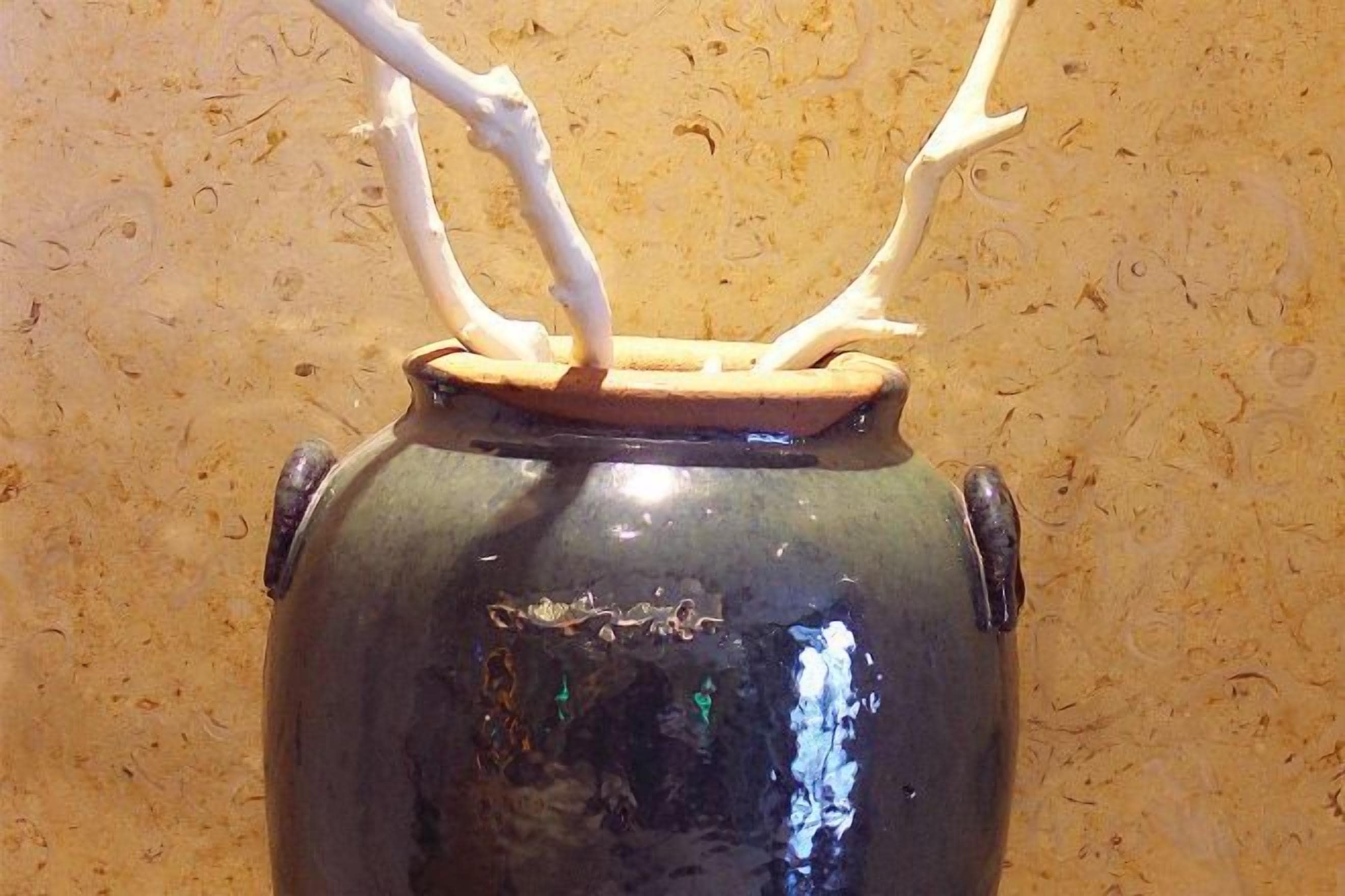 A ceramic pot with a lid and two handles.