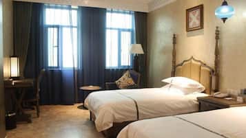 Een hotelkamer met twee bedden, een bureau, een stoel, een lamp en een nachtkastje.