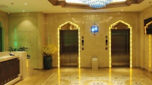 Un hall d’entrée doté de deux ascenseurs, d’un comptoir de réception et d’un lustre.