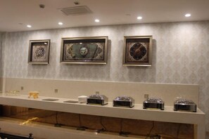 A wall with framed artwork and a long counter with various items. - Konghe Yizhan Culture Hotel (Turpan)