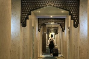 Un couloir aux murs et au plafond ornés de motifs, qui mène à une pièce.