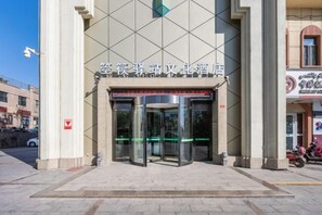 A hotel entrance with a revolving door and a sign above it. - Konghe Yizhan Culture Hotel (Turpan)