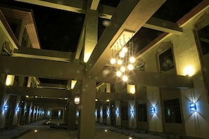 A building with a covered outdoor area, multiple light fixtures, and a clear sky. - Konghe Yizhan Culture Hotel (Turpan)