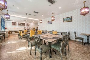 Un ristorante con diversi tavoli e sedie, carta da parati decorata e lanterne appese.
