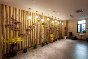 A reception area with a wooden wall, potted plants, and a seating area. - Konghe Yizhan Culture Hotel (Turpan)