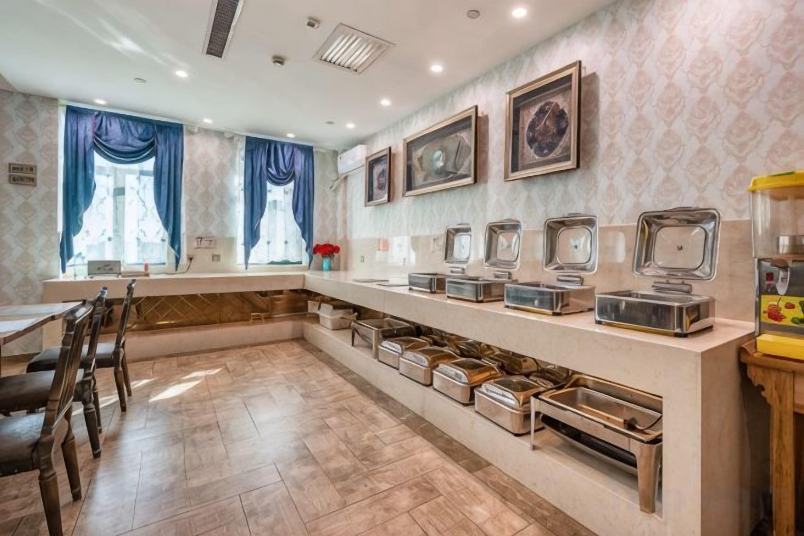Un espace de restauration d'hôtel comprenant un long comptoir, plusieurs distributeurs de nourriture et des tables où les clients peuvent s'asseoir.