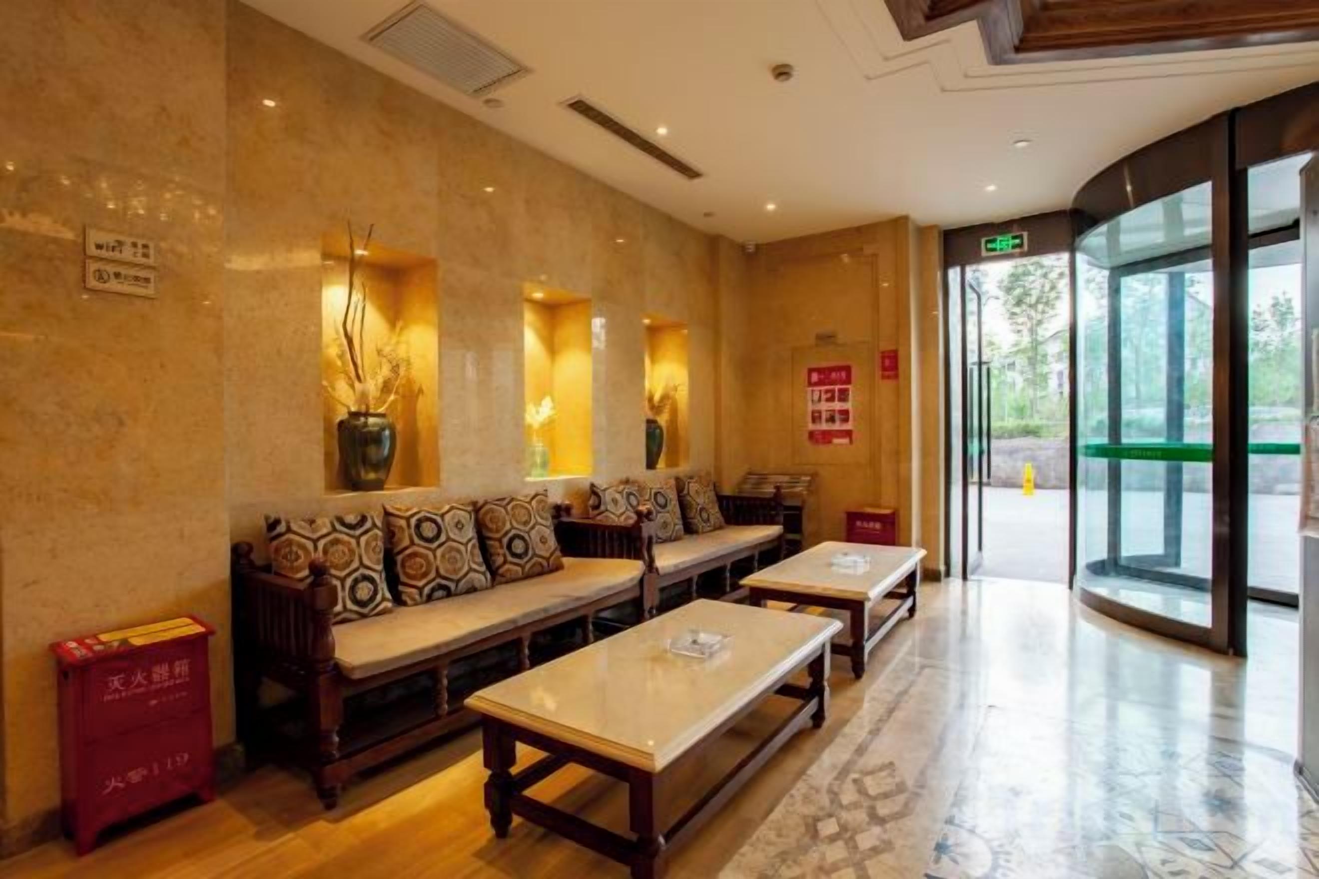 A hotel lobby with seating areas, a reception desk, and a glass entrance.