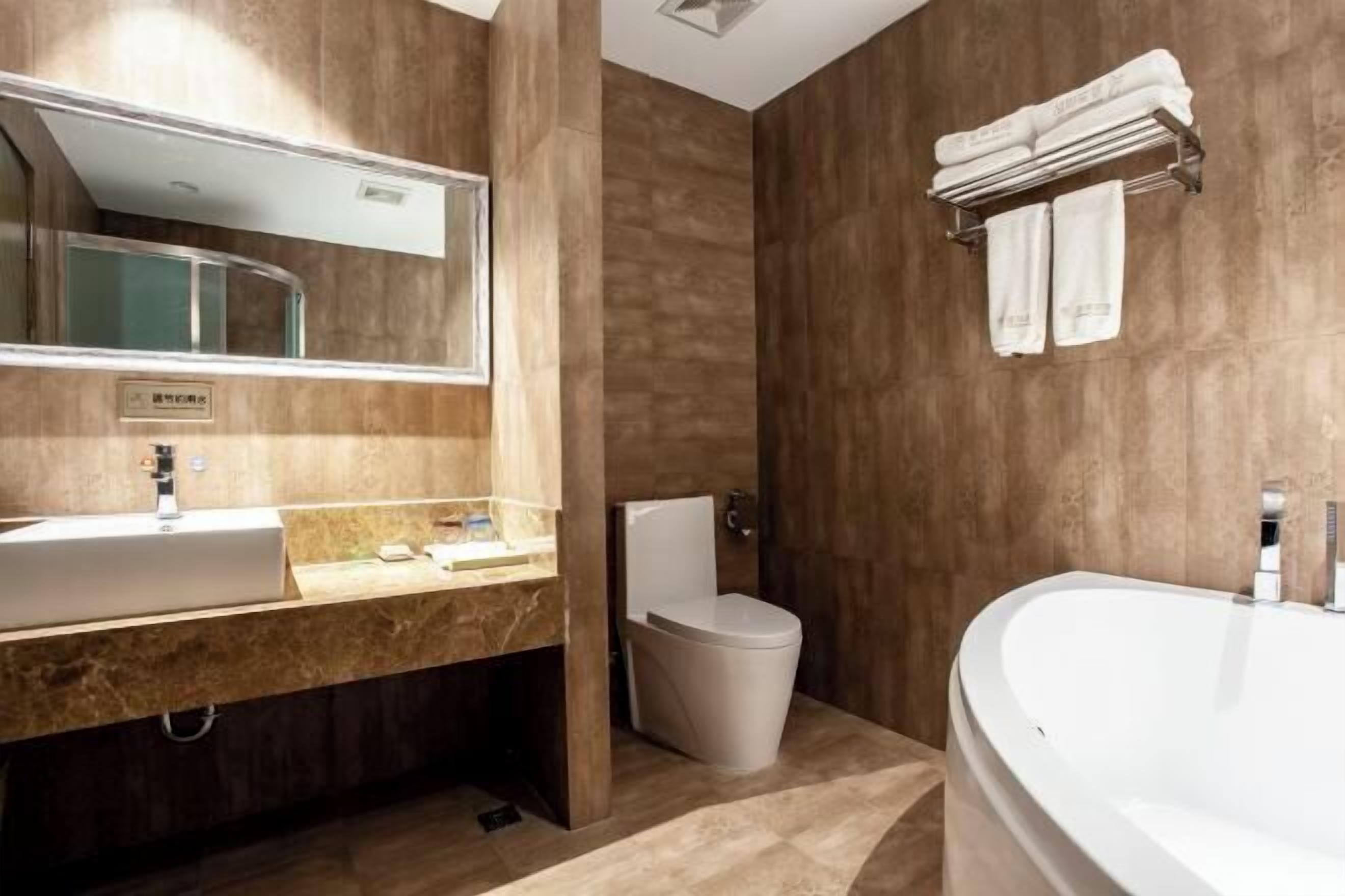 Un baño moderno con un espejo grande, un lavamanos, un inodoro y una bañera.