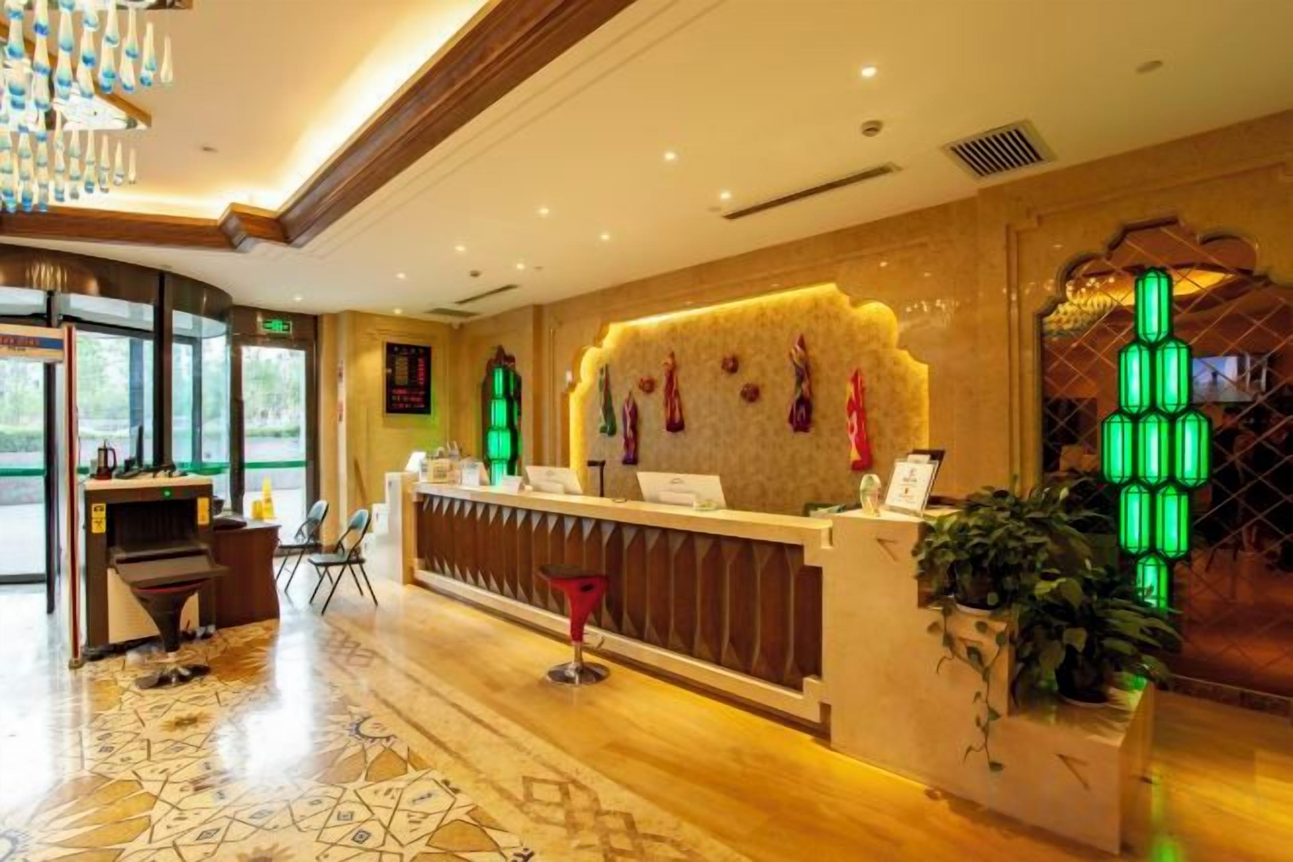 A hotel reception area with a reception desk, a seating area, and a large window.