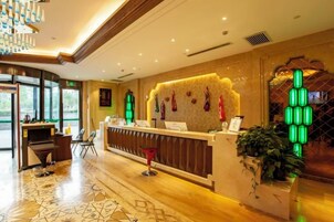 Zona de recepción de un hotel con mostrador, área de descanso y un ventanal grande.