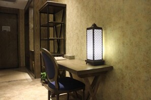 Un escritorio de madera con una silla, un estante en la pared y un farol encendido.