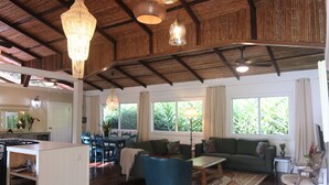 Amplia sala de estar con techo de madera, un sofá, una mesa de centro y un comedor con sillas y una mesa.