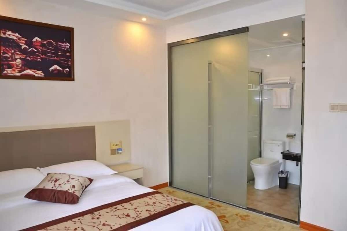 Une chambre dâhĂŽtel comprenant un lit, une table de chevet, un espace douche et une salle de bain.