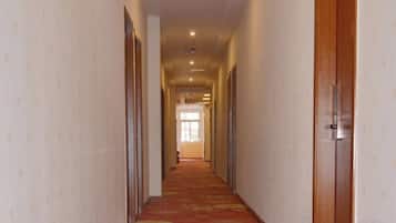 Un pasillo con puertas a ambos lados que conduce a una habitación con ventanal.