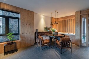 A modern kitchen with a dining area, wooden walls, and a large window.