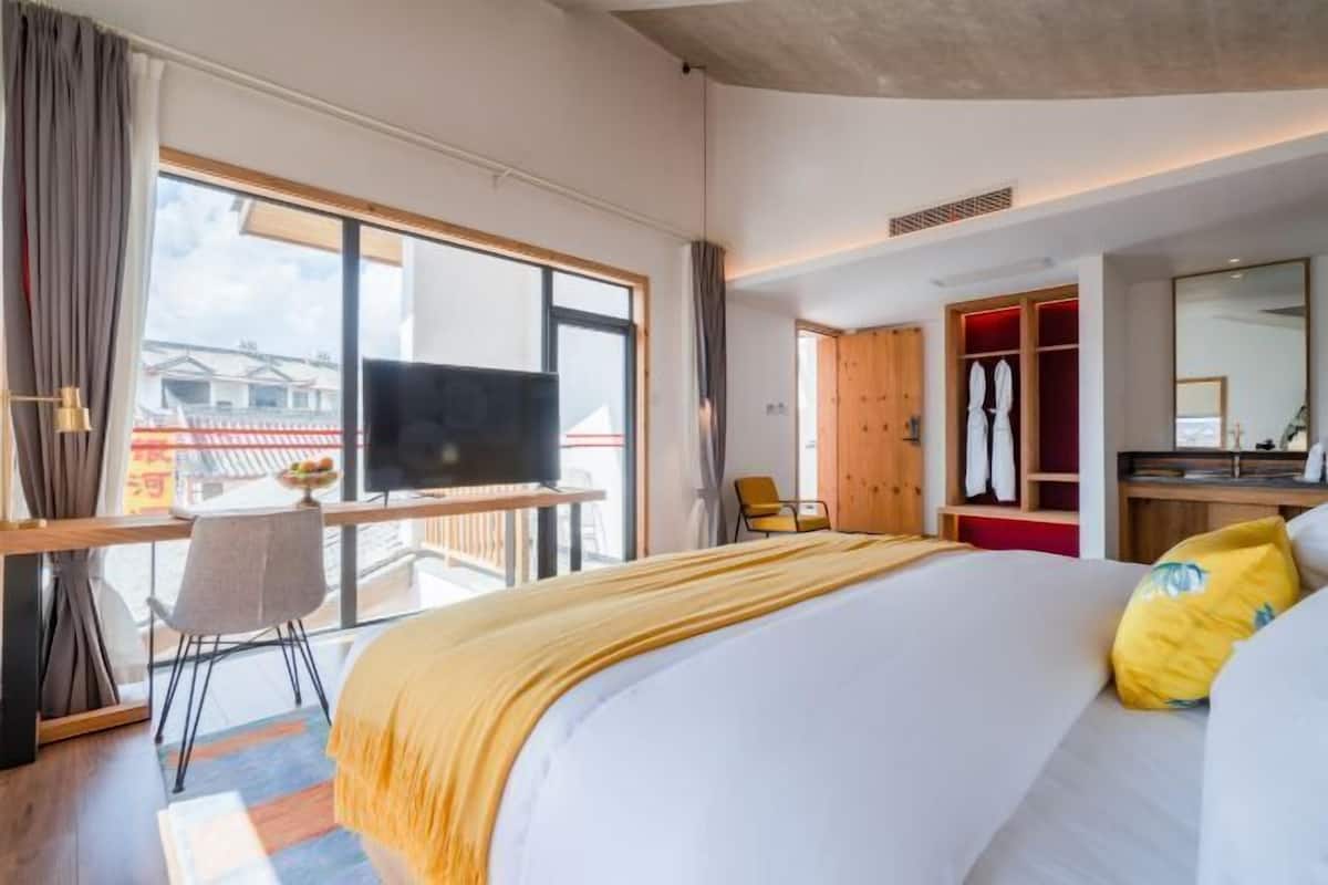 Een hotelkamer met een groot bed, een televisie, een bureau, een stoel en een kledingkast.