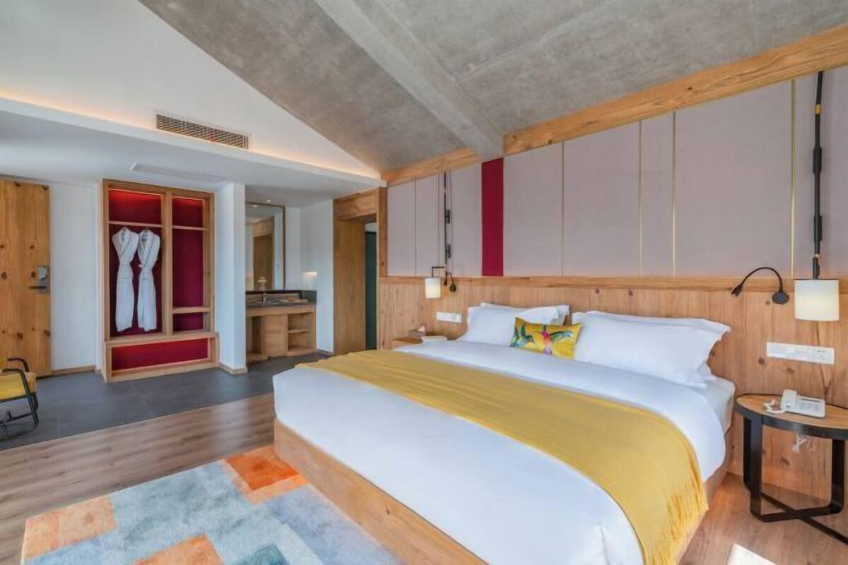 Een moderne hotelkamer met een groot bed, een houten hoofdbord en een inloopkast met rode accenten.