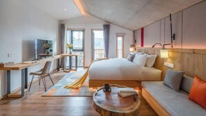 Habitación de hotel moderna con cama, sofá, escritorio y vistas al exterior.